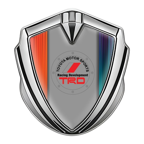 Toyota Emblem Abzeichen Silbertonfarbe mit Orangeblaue Kratzer Hintergrund und TRD Logo