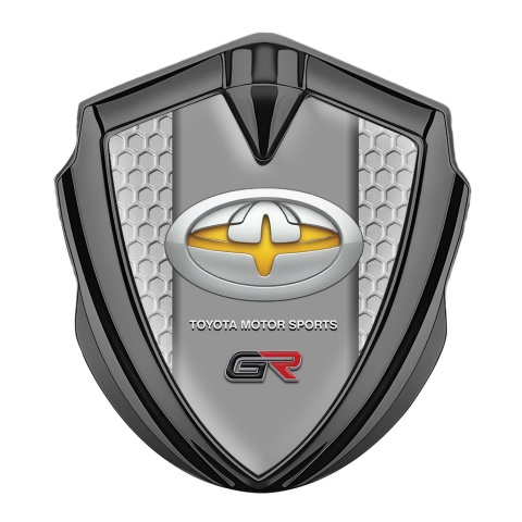 Toyota GR Abzeichen selbstklebend Graphit Tonfarbe mit Wabeneffekt Hintergrund und Gelb Motiv Logo