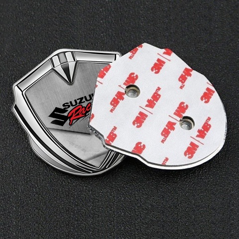 Suzuki Emblem Auto Zeichen Silbertonfarbe Asphalt mit Steinen Fundament und Racing Logo