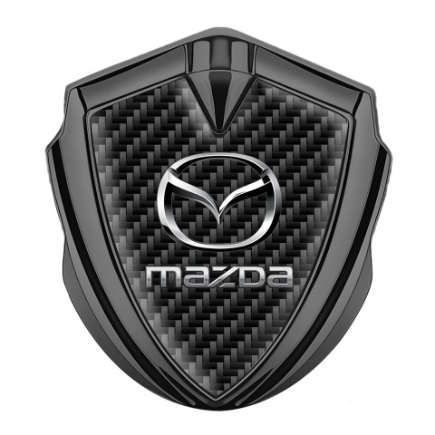 Mazda Emblem Abzeichen selbstklebend Graphit Tonfarbe mit Schwarz Carbon Hintergrund und Klassisch Logo