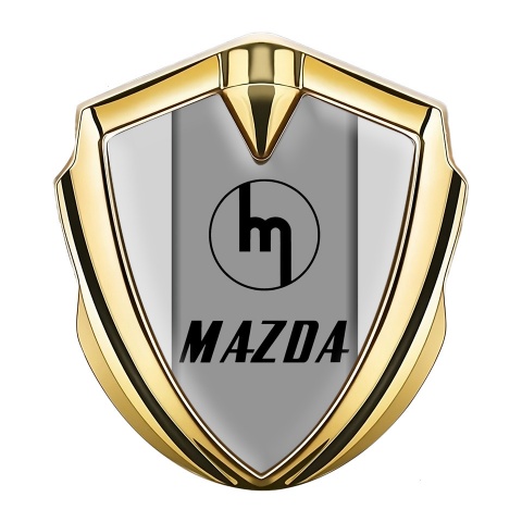 Mazda Emblem Abzeichen Goldtonfarbe mit Grau Hintergrund und Retro Logo Design