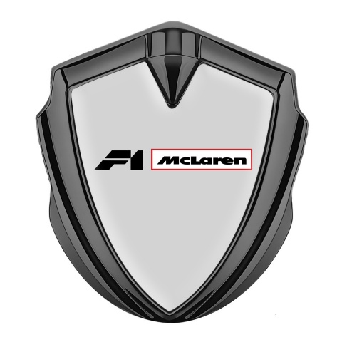 Mclaren Emblem Abzeichen selbstklebend Graphit Tonfarbe Grau Hintergrund mit F1 Logo