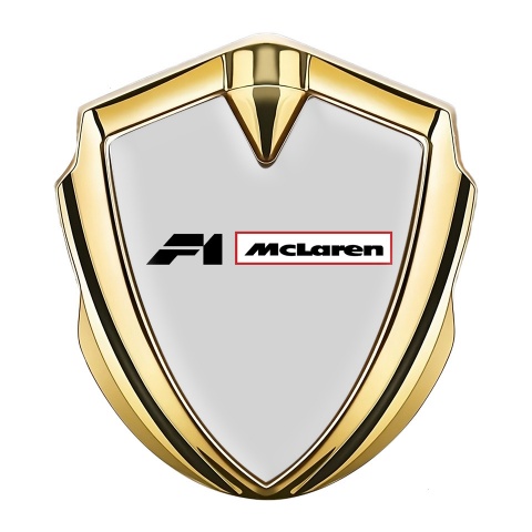Mclaren Emblem Abzeichen selbstklebend Goldtonfarbe Grau Hintergrund mit F1 Logo
