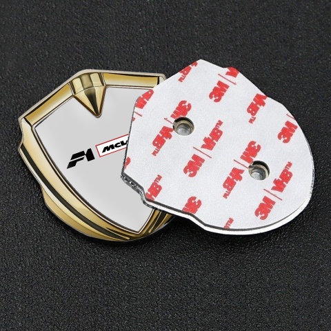 Mclaren Emblem Abzeichen selbstklebend Goldtonfarbe Grau Hintergrund mit F1 Logo
